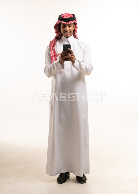 رجل سعودي بالزي التقليدي يستخدم الهاتف الذكي في الاستوديو