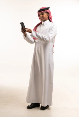 رجل سعودي بالثوب التقليدي يستخدم الهاتف الذكي