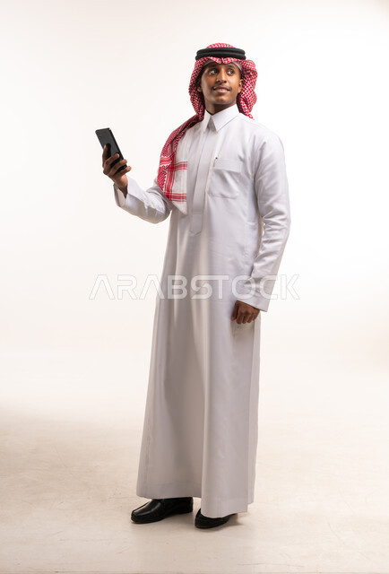 Saudi Man in Traditional Thobe Holding Smartphone Studio