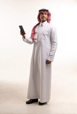 رجل سعودي بالزي التقليدي يحمل هاتف ذكي في استوديو