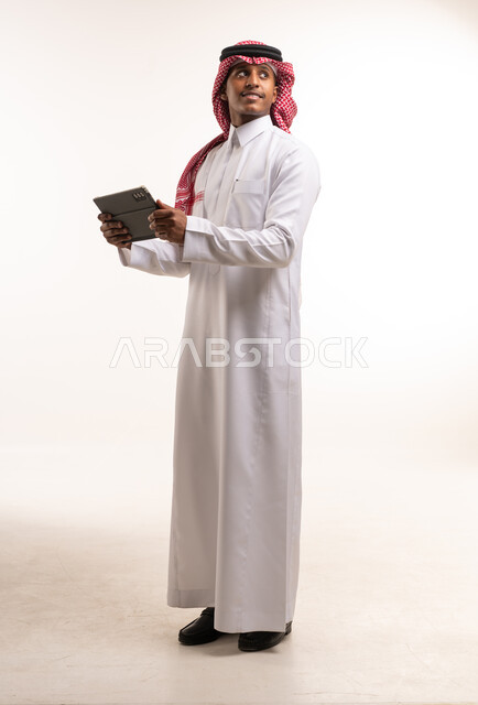 رجل سعودي يحمل جهاز لوحي بخلفية بيضاء