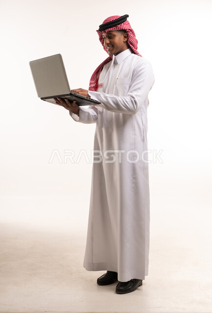 رجل سعودي يستخدم الحاسوب المحمول بخلفية بيضاء