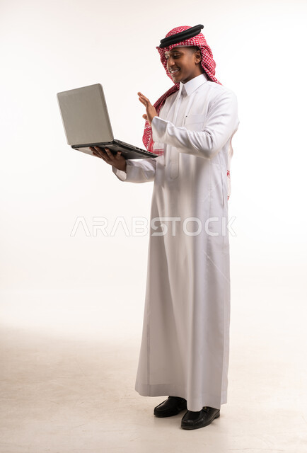 رجل سعودي يستخدم الحاسوب المحمول أمام خلفية بيضاء