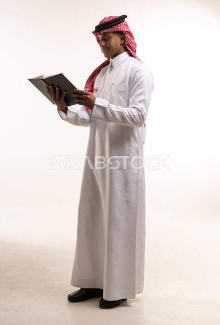 رجل سعودي بالثوب التقليدي يقرأ كتاباً