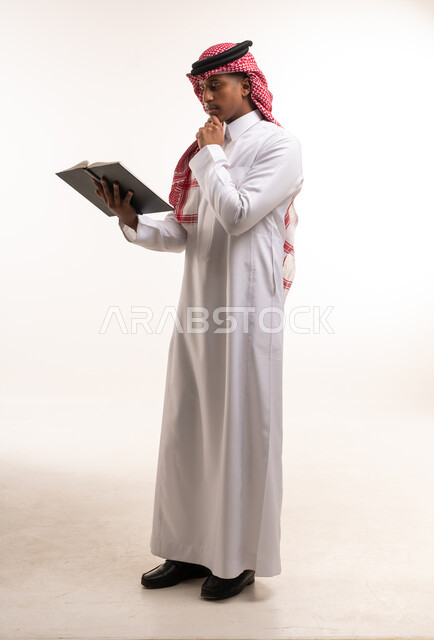 رجل سعودي بالزي التقليدي يقرأ كتاباً