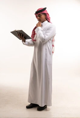 Saudi Man in Traditional Thobe Reading a Book