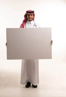 طبيب سعودي يحمل لوحة بيضاء فارغة بخلفية بيضاء