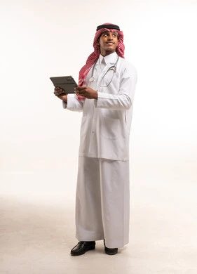 طبيب سعودي يحمل جهاز لوحي وسماعة طبية