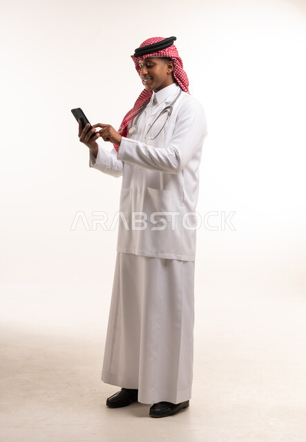Saudi Male Doctor in Lab Coat Using Smartphone Studio Shot