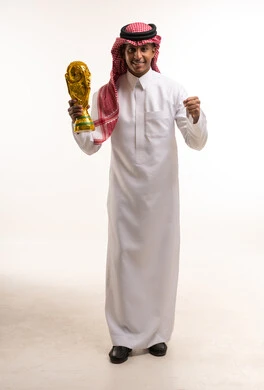 رجل سعودي يحمل كأس كرة قدم ذهبي في استوديو
