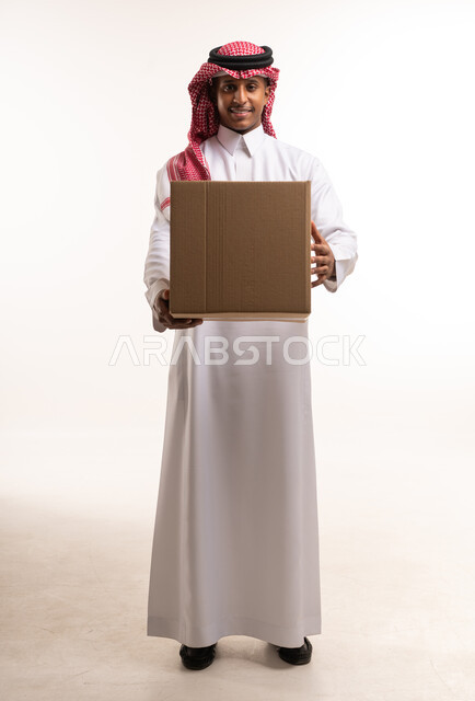 رجل سعودي يحمل صندوق شحن كرتوني في الاستوديو