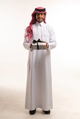 رجل سعودي بالزي التقليدي يمسك صندوق هدايا