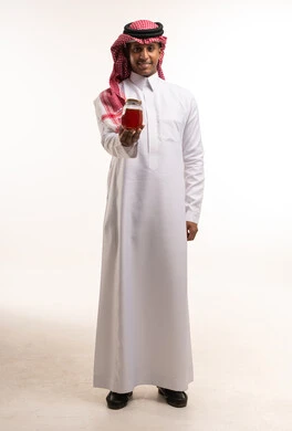 رجل سعودي بالثوب التقليدي يحمل جرة عسل