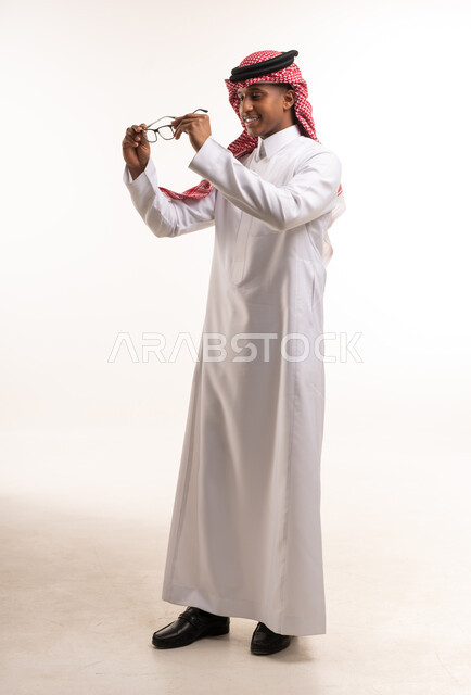 رجل سعودي بالزي التقليدي يحمل نظارة طبية في الاستوديو