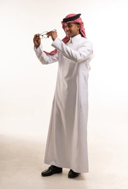 رجل سعودي بالزي التقليدي يحمل نظارة طبية في الاستوديو