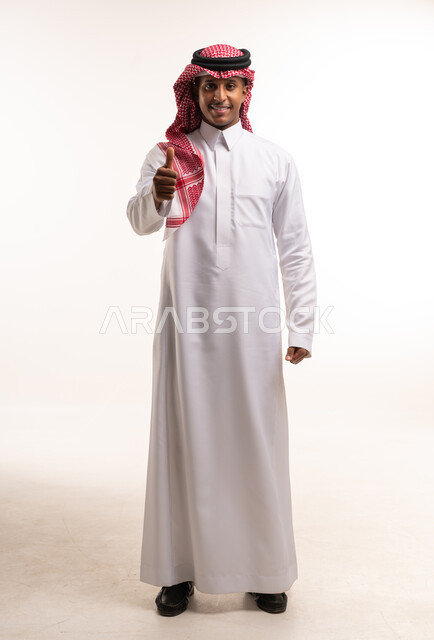 رجل سعودي بالزي التقليدي يرفع إبهامه للموافقة