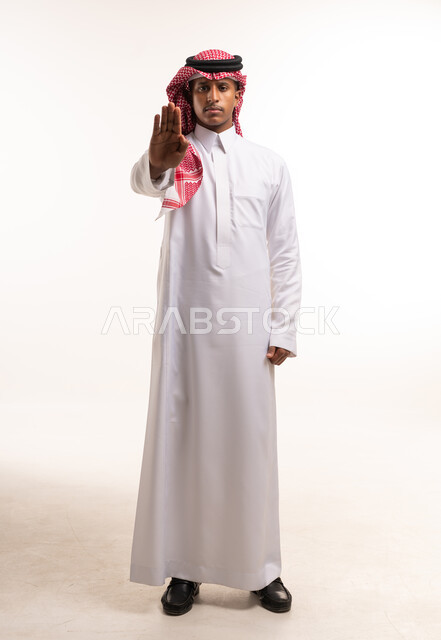 رجل سعودي يقوم بإشارة توقف بالزي التقليدي