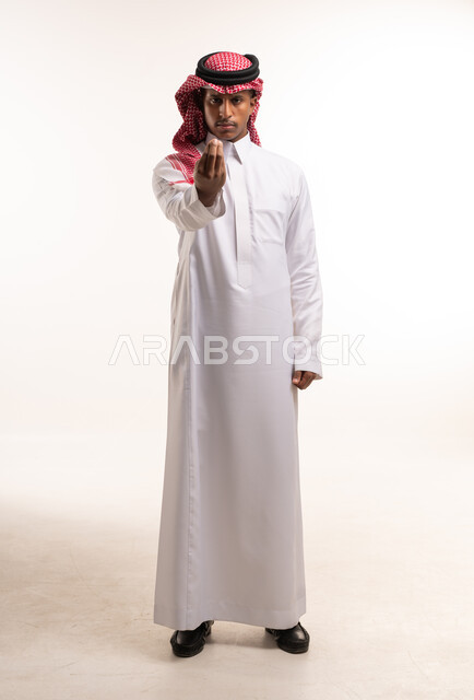 رجل سعودي بالثوب التقليدي والشماغ يقوم بإيماءة يد