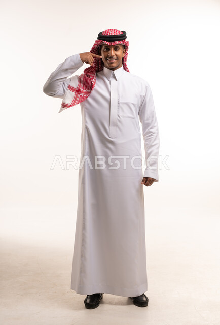 رجل سعودي بالزي التقليدي يشير إلى ابتسامته