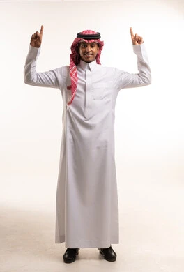 رجل سعودي بالزي التقليدي يشير إلى الأعلى في استوديو