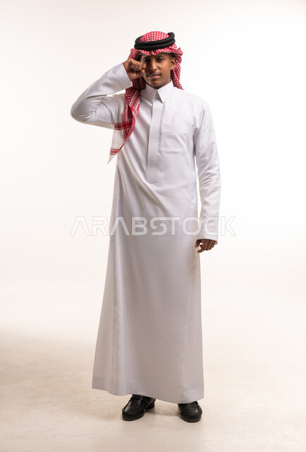 رجل سعودي بالثوب التقليدي يمسح عينه بالاستوديو