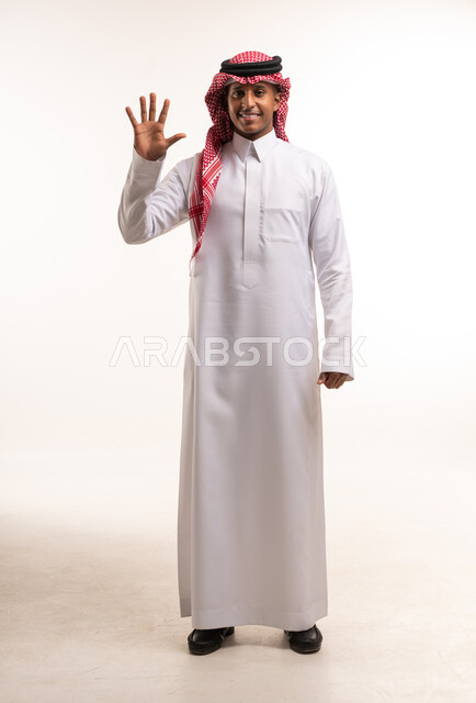 رجل سعودي يرتدي الثوب التقليدي يشير برقم خمسة بيده
