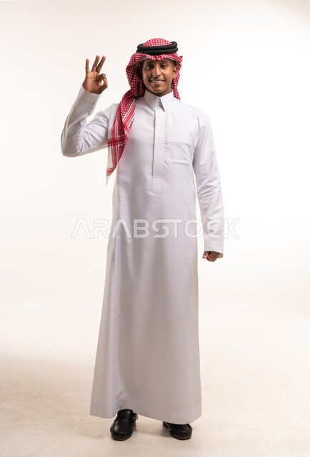 رجل سعودي بالزي التقليدي يشير بعلامة التمام