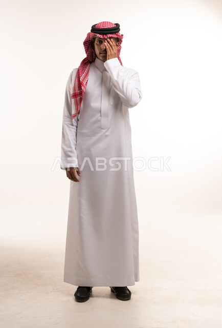 رجل سعودي بالزي التقليدي يغطي عينه في الاستوديو