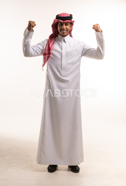 رجل سعودي بالثوب التقليدي يستعرض عضلاته في الاستوديو