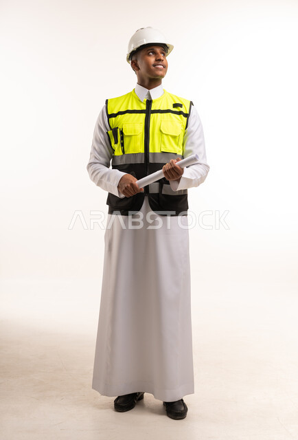 مهندس سعودي بالثوب التقليدي يحمل مخططاً هندسياً