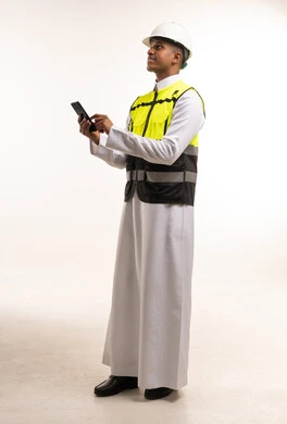 مهندس سعودي يرتدي سترة السلامة ويستخدم الهاتف