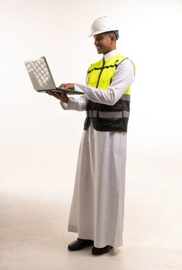 مهندس سعودي يرتدي خوذة ويستخدم حاسوب محمول