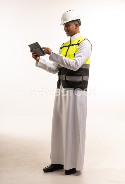 مهندس سعودي بالثوب التقليدي يستخدم جهاز لوحي