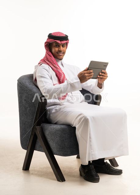 رجل سعودي يحمل جهاز لوحي بخلفية بيضاء