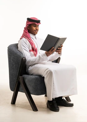 Saudi Man in Traditional Attire Reading Book in Studio