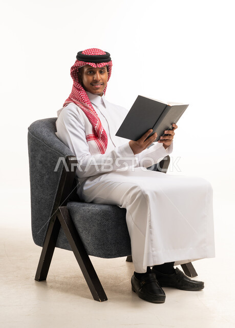 Saudi Man in Traditional Thobe Reading Book in Studio