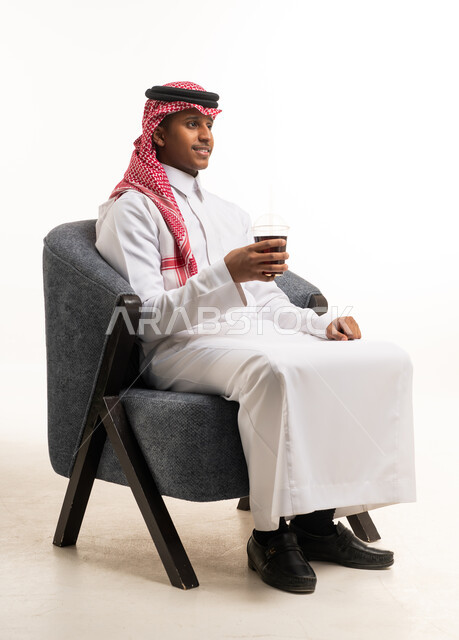 رجل سعودي بالزي التقليدي جالساً مع مشروب