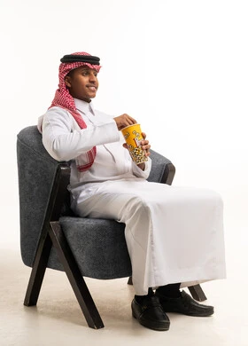 رجل سعودي بالزي التقليدي يأكل الفشار في الاستوديو