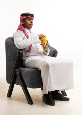 Saudi Man in Traditional Thobe Watching Movie with Popcorn