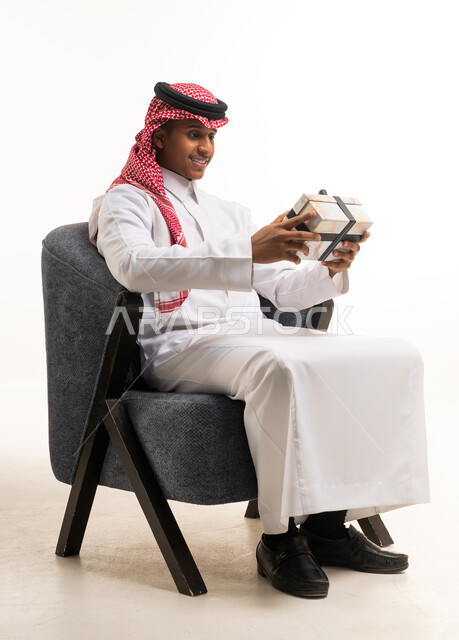 رجل سعودي بالزي التقليدي يحمل صندوق هدايا