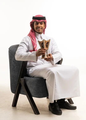 رجل سعودي بالزي التقليدي يمسك مبخرة خشبية