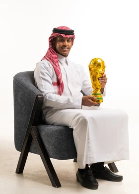 رجل سعودي بالزي التقليدي يحمل مجسم كأس العالم