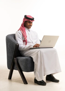 Saudi Man in Traditional Thobe Using Laptop on White