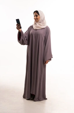 امرأة عربية بعباية موف وحجاب تستخدم الهاتف الذكي