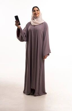 امرأة سعودية بعباءة وهاتف ذكي في استوديو