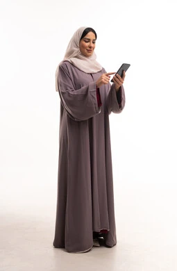 امرأة عربية بالعباءة تستخدم الهاتف الذكي في الاستوديو