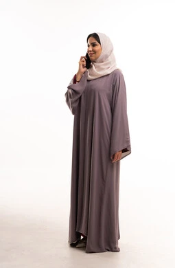 امرأة سعودية بالعباءة والحجاب تستخدم الهاتف الذكي في استوديو