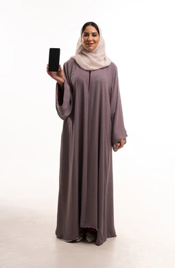 امرأة إماراتية تحمل هاتفاً ذكياً بشاشة فارغة امرأة إماراتية تحمل هاتفاً ذكياً بشاشة فارغة