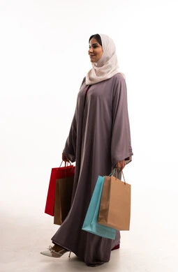 امرأة سعودية تحمل حقائب تسوق بالعباية التقليدية