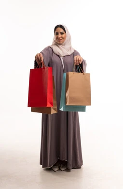 امرأة عربية بالعباية تحمل حقائب تسوق في الاستوديو